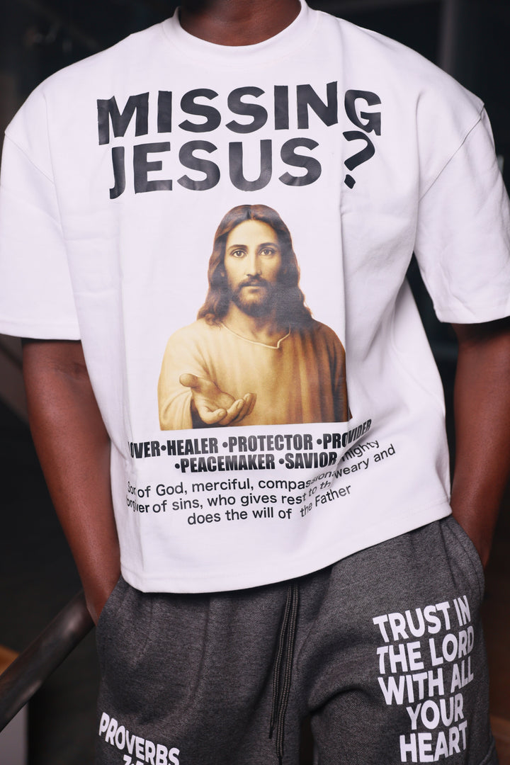 Person wearing a white t-shirt with a graphic and text, sitting on a vehicle seat.